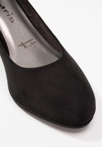 Černé semišové vysoké podpatky, zaoblená špička, měkká textura, s kovově stříbrnou stélkou a brandingem "touch it". Minimalistický design.