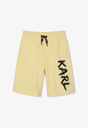 Shorts jaune clair avec cordon noir et grand texte noir "KARL" imprimé verticalement sur la jambe droite, avec poches latérales.