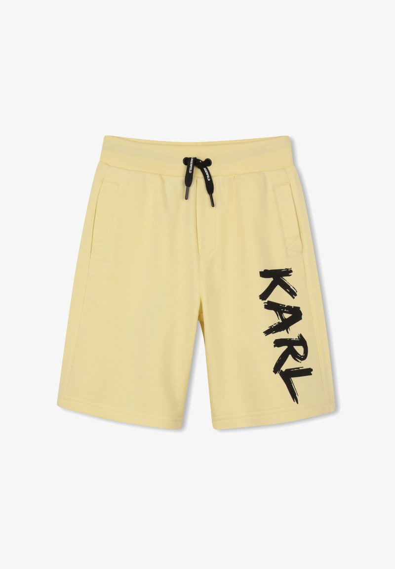 Shorts jaune clair avec cordon noir et grand texte noir "KARL" imprimé verticalement sur la jambe droite, avec poches latérales.