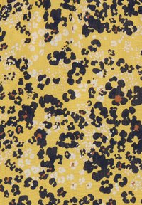 Keltainen kangas, jossa on teksturoidun pinnan ja leopardikuvio mustana, valkoisena ja ruskean sävyillä, erilaisilla pistekoolla.