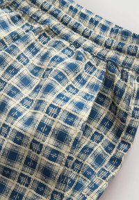 Tissu à carreaux bleu et blanc avec motif quadrillé texturé et détail de taille élastique.