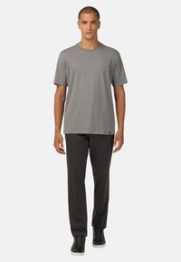 T-shirt en coton gris à manches courtes, assortie à un pantalon noir et des baskets noires avec des lacets et des accents de semelle contrastés.