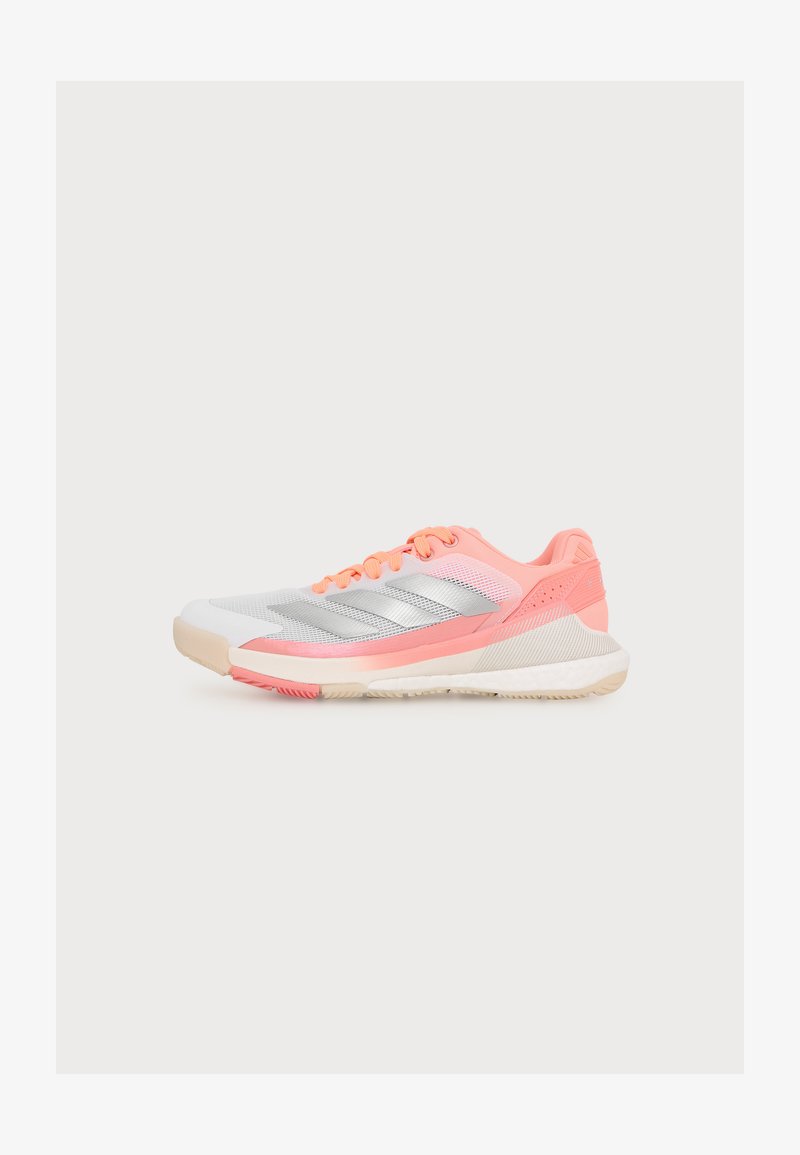 Chaussure de sport gris clair et corail avec des bandes argentées, une semelle coussinée et des lacets corail, présentée de profil sur fond blanc.