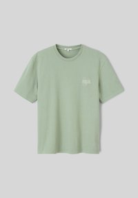 T-shirt en coton vert clair à manches courtes, avec un col rond et un petit motif graphique blanc sur la zone du côté gauche de la poitrine.