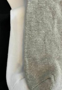 Drei gefaltete Socken aus schwarzem, weißem und grauem Strickstoff, die nebeneinander gestapelt sind.