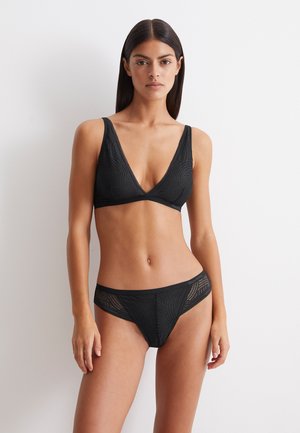 Zwart lingerieset bestaande uit een diepe V-hals bralette met een gestructureerd patroon en brede banden, gecombineerd met bijpassende slips met ingewikkelde details.