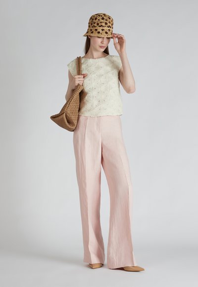 Top chiaro a fantasia floreale, pantaloni ampi rosa soft, cappello a secchiello in paglia intrecciata e una borsa tote marrone testurizzata, completano l'outfit.
