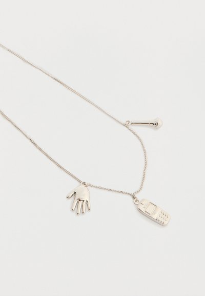 Ασημένιο κολιέ αλυσίδα με μενταγιόν στο σχήμα χεριού, παλιού κινητού τηλεφώνου και μικρού μικροφώνου σε λευκό φόντο.