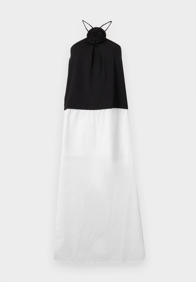 Robe halter noir et blanc présentant un détail en rose au niveau du col, avec un haut ajusté et une jupe blanche fluide. Texture de tissu douce.