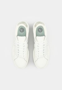 White sneakers with smooth leather upper, lace-up design, padded tongue, and light green insole featuring a circular logo.