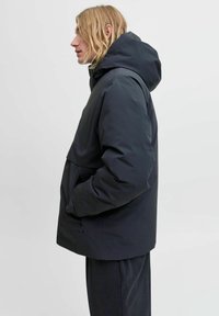 Donkerblauwe, met capuchon uitgeruste jas met een hoekig ontwerp, een voorzak en een gladde, matte textuur. Voorzien van steekzakken aan de zijkant en verstelbare trekkoorden.