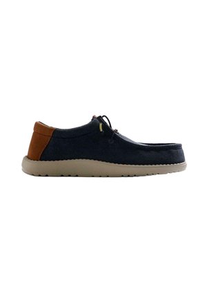 Scarpa casual slip-on blu navy con toppa marrone sul tallone, suola beige e lacci neri, mostrata di profilo su sfondo bianco.