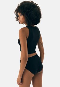 Black crop top with ribbed texture and sleeveless design, paired with high-waisted black shorts. Simple and minimalistic style.