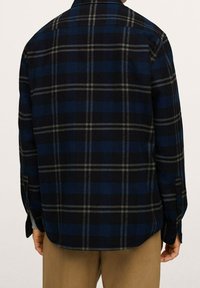 Camicia a quadri nei toni di blu, nero e grigio, con colletto button-down, maniche lunghe e una vestibilità comoda con dettagli sul retro.