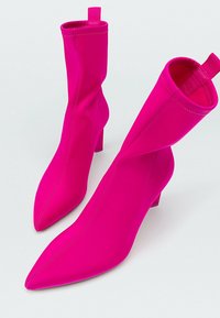 Fuchsia ankle boots made from stretch fabric, featuring a pointed toe and a low block heel, with a pull tab at the back for easy wear.