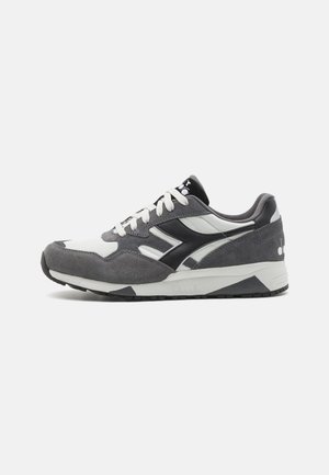 Sneaker atletica grigia e bianca realizzata in morbido camoscio e rete, con logo nero, lacci bianchi e suola con motivo.