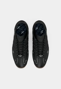 Pair of black Adidas sneakers with white stitching and Adidas logos on the tongue and insoles, viewed from above on a white background.