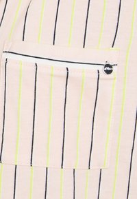 Lichtroze stof met verticale strepen in zwart en neon groen. Opvallende zak met een witte rand en een klein metalen detail.