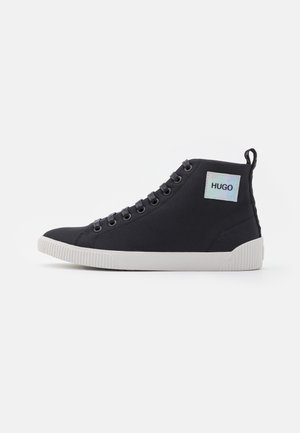 Schwarzer High-Top-Sneaker mit weißer Sohle, Schnürung vorne, Zuglasche hinten und einem "HUGO" Logo-Patch an der äußeren Knöchelseite.