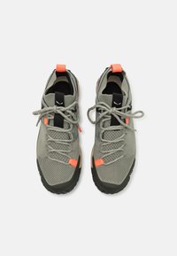 Scarpe sportive grigio chiaro realizzate in rete e tessuto. Presentano accenti neri, linguette arancioni sul tallone e una suola nera resistente. I lacci sono legati.