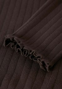 Bruin geribbeld textiel met een gestructureerd patroon, voorzien van een geplooide rand. Zacht materiaal met langwerpige verticale lijnen.