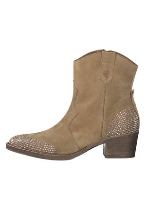 Bottine cheville en daim beige avec un bout pointu, ornée de strass sur le bout et le talon. Dispose d'un petit talon empilé et de coutures courbes.