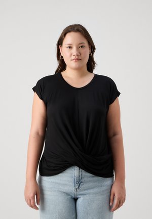 Black short-sleeve top with a V-neck, featuring a twisted front design. Smooth, lightweight fabric paired with light blue high-waisted jeans.