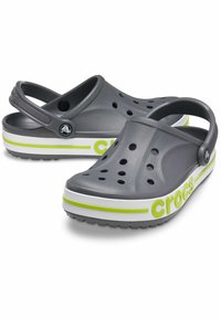 Szare klapki Crocs z wieloma otworami wentylacyjnymi, regulowanym paskiem z tyłu oraz białą i neonowo-zieloną paskiem akcentowym. Teksturowana podeszwa zapewniająca przyczepność.