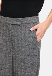 Hondstooth-gepatroneerde broek van grijs en zwart stof, met een platte voorkant, tailleband en zijzakken. Gladde textuur met een op maat gemaakte pasvorm.