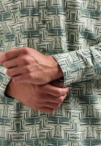 Groene en crèmekleurige button-up shirt met een gestructureerd geweven patroon. Mouwen omgeslagen, met een sluiting met twee knopen en een ontspannen pasvorm.