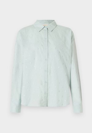 Gaiši zils krekliņš ar apkakli, garām piedurknēm un teksturētu rakstu ar maziem apļveida punktiem visā virsmā.