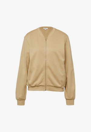 Veste zippée beige en tissu doux avec un col rond, des poignets et une taille élastiques. Dispose d'une fermeture éclair à l'avant et d'une texture lisse.