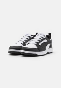 Athletic sneakers in black and white, featuring a textured leather upper, perforated toe box, white laces, and a rubber sole with contrasting accents.