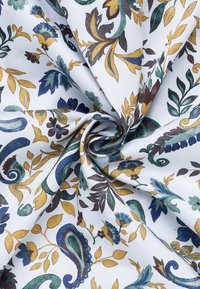 Gepatineerde stof met een witte achtergrond en meerkleurige bloemen- en paisleypatronen in blauw, groen, geel en bruin.