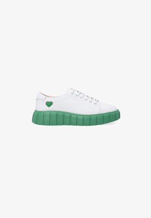 White sneaker with a thick green rubber sole, featuring a textured design. Notable green heart accent on the side. Standard lace-up closure.