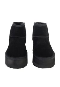 Stivali alla caviglia in suede nero con suola piatta e spessa. Presentano una punta arrotondata e un bordo rinforzato, con dettagli di cucitura minimi.