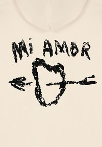 Felpa color crema con stampa grafica nera che presenta la scritta "Mi Amor" e un cuore trafitto da una freccia, design testurizzato e astratto.