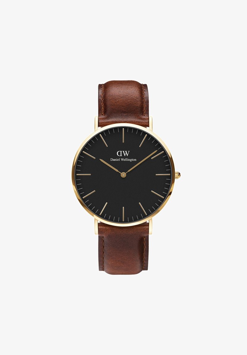 Zwart wijzerplaat horloge met gouden kast, verlengde uurmarkeringen en bruine lederen band. Minimalistisch ontwerp met eenvoudige wijzers. Messing accenten.