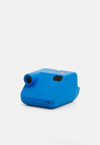 Blue instant camera with a rounded body, a lens protruding from one side, a red button on top, and a compact design.