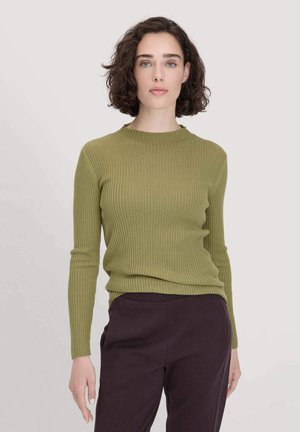 Maglione a coste verde oliva con colletto rotondo, maniche lunghe e design aderente, abbinato a pantaloni viola scuro.