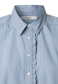 Gaiši zils rāvējsudraba krekls ar pogām uz leju, maigi viļņota detaļa ap apģērba pogu un parastām baltām pogām.