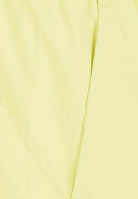 Primer plano de tela amarillo claro con costuras y detalles de puntadas visibles.