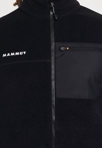 Black fleece jacket with zippered front, feature black zippered chest pocket, and white embroidered "MAMMUT" logo on left side.