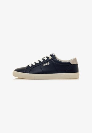 Zapatillas de cuero azul marino con cordones blancos, acento en el talón beige y suela de goma texturizada. Presenta un logo en el lateral y un cuello acolchado.