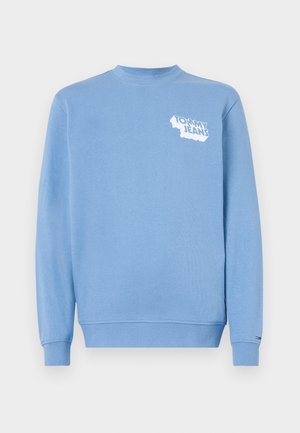 Šviesiai mėlynas džemperis minkštos tekstūros, su baltu "Tommy Jeans" logotipu kairėje krūtinės pusėje. Gūžtės apykaklė ir rankogaliai su raukiniais.