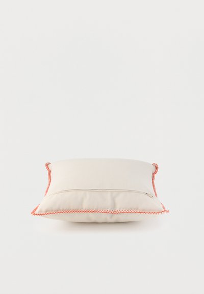 Coussin rectangulaire beige avec couture zigzag orange le long des bords sur fond blanc uni.