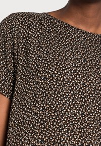 Top de tela con estampado floral en negro, que presenta pequeñas flores blancas y melocotón, mangas cortas y un escote amplio. Textura suave.
