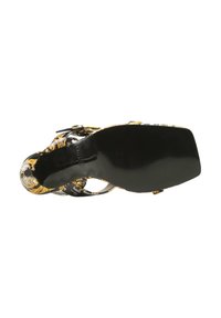 Sandal à talons hauts avec une finition en vernis noir, ornée d'un audacieux motif floral jaune et noir. La semelle est lisse et plate avec un bord texturé.