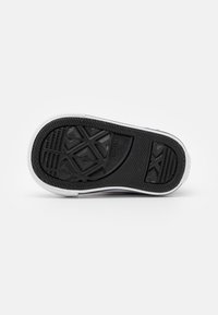 Gumová podrážka s černým vzorovaným gripem, bílými okraji a texturovanými povrchy pro lepší trakci.