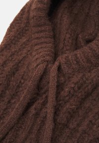 Brun stickad tröja med en kraftig textur, tjocka ribbmönster, en sjalkrage och dragsko. Mjuk ull-liknande material.